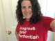A selfie of Meryl Evans wearing a red T-shirt that says 'Progress Over Perfection'