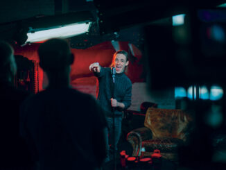 Shooting a stand-up show. Stand-up comedian on stage at the microphone.