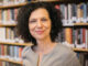 color photo headshot of Professor Batja Mesquita in front of a large bookshelf