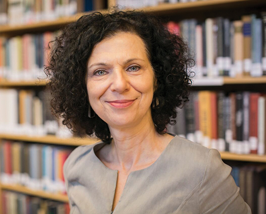 color photo headshot of Professor Batja Mesquita in front of a large bookshelf